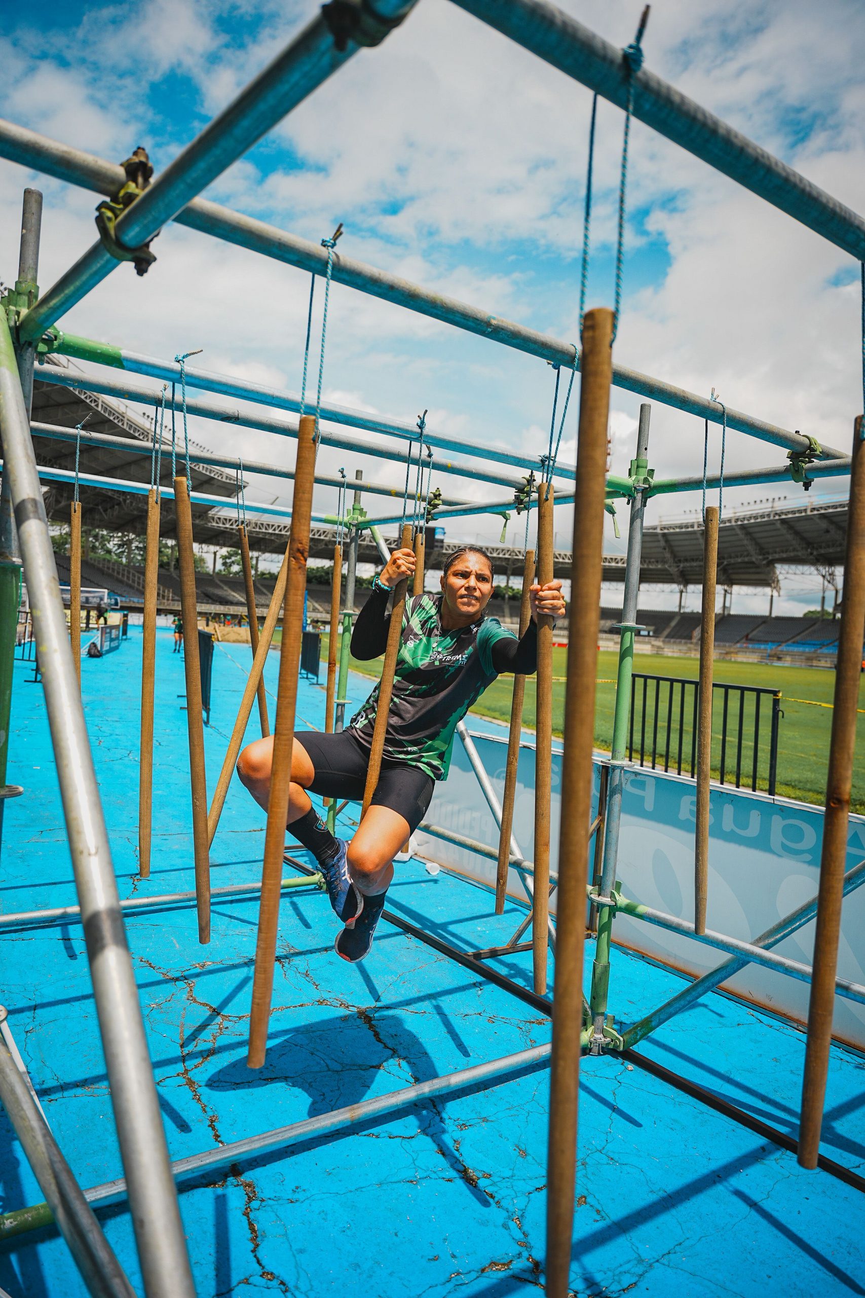 A woman skillfully navigates an obstacle course in an outdoor stadium, showcasing strength and agility.